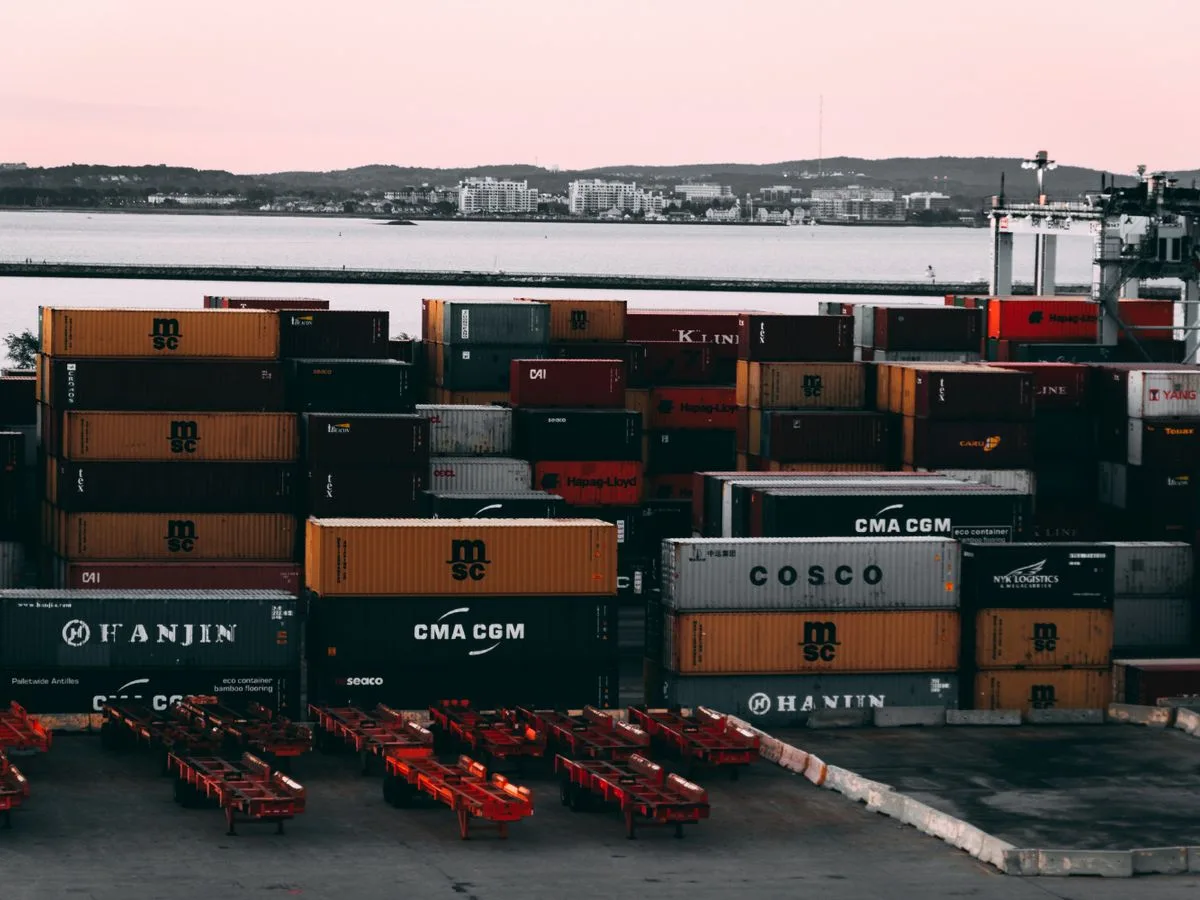 Shipping containers stacked in a port container yard at twilight