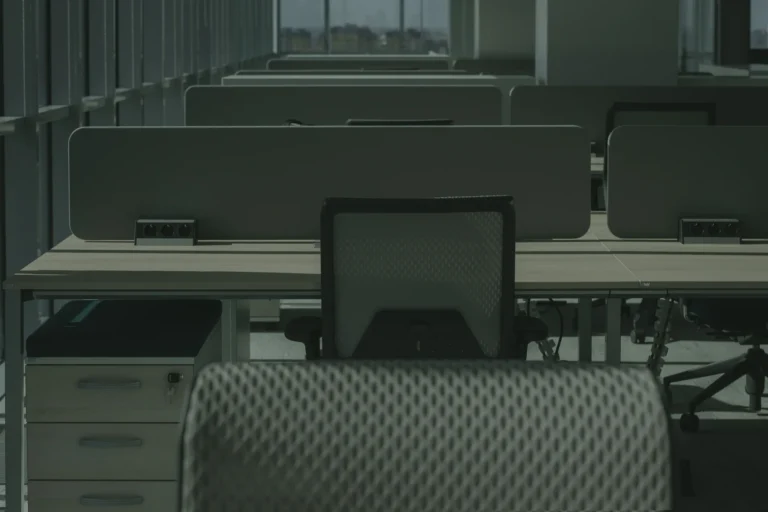 Rows of empty desks and office chairs in a modern open plan office