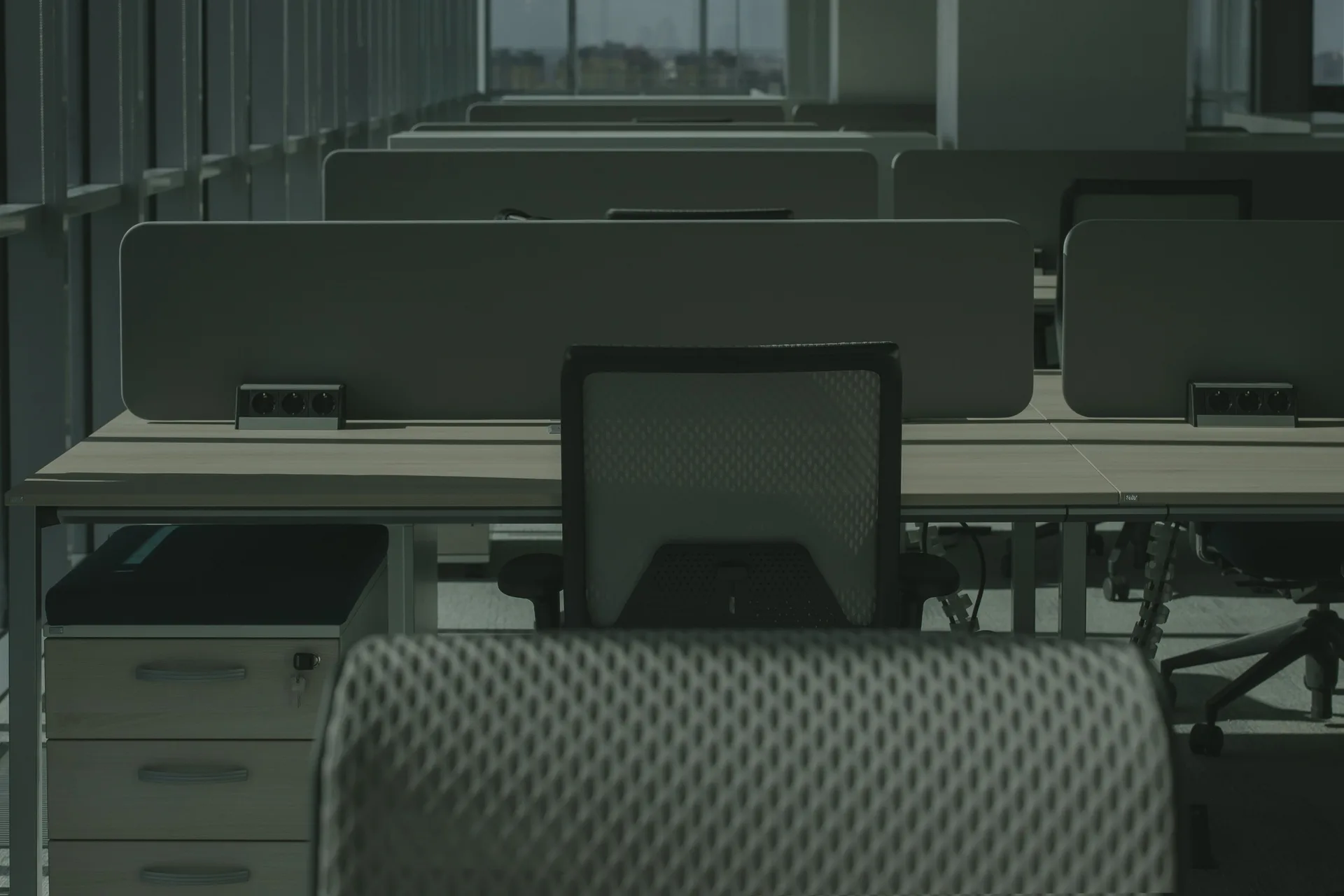 Rows of empty desks and office chairs in a modern open plan office