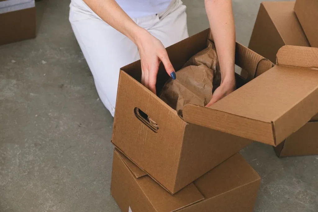 Fragile items being wrapped and packed into a cardboard box