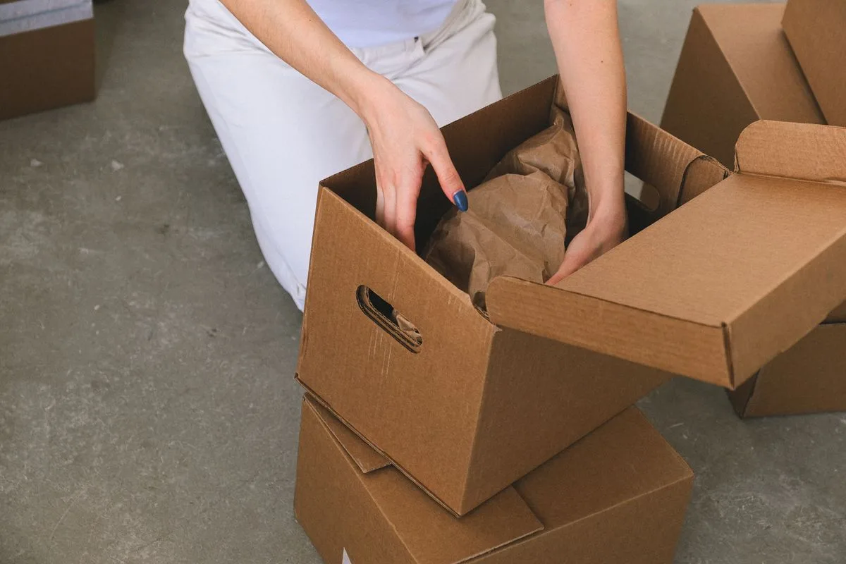 Fragile items being wrapped and packed into a cardboard box
