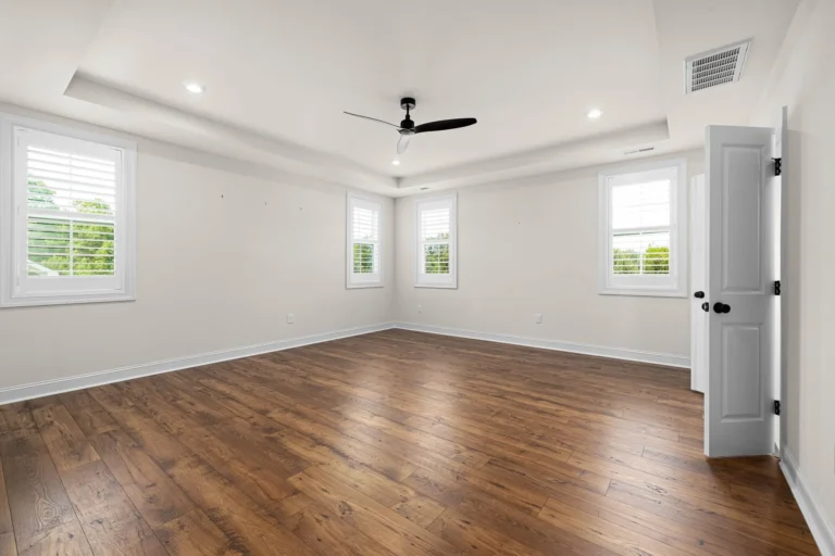 Bright empty room with wooden flooring and white walls awaiting furniture