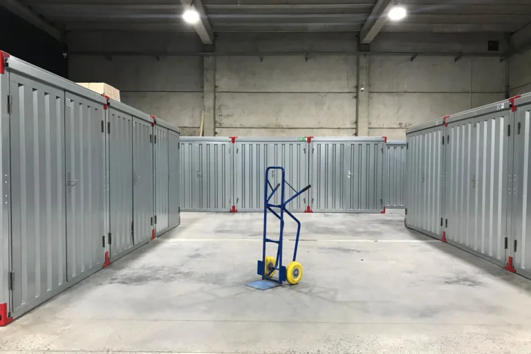 A plain storage building interior with steel doors and a hand truck