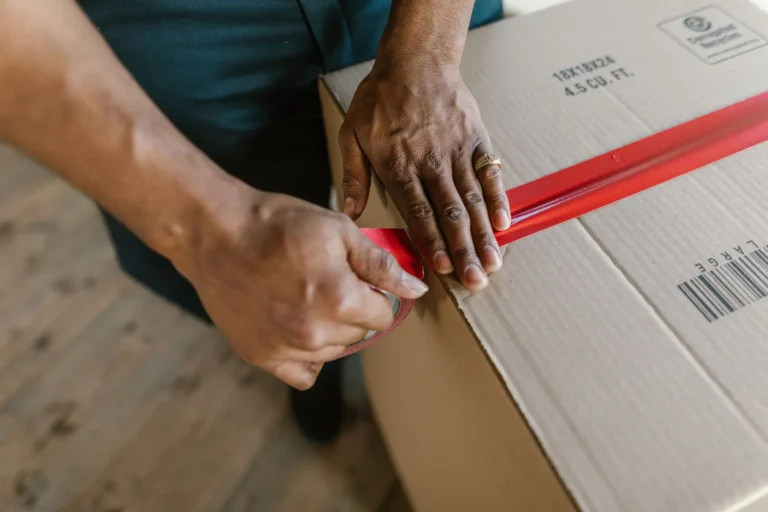 Close up of packing tape being run along the seam of a cardboard box
