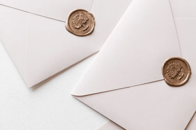 Three sealed white envelopes arranged on a pale table top